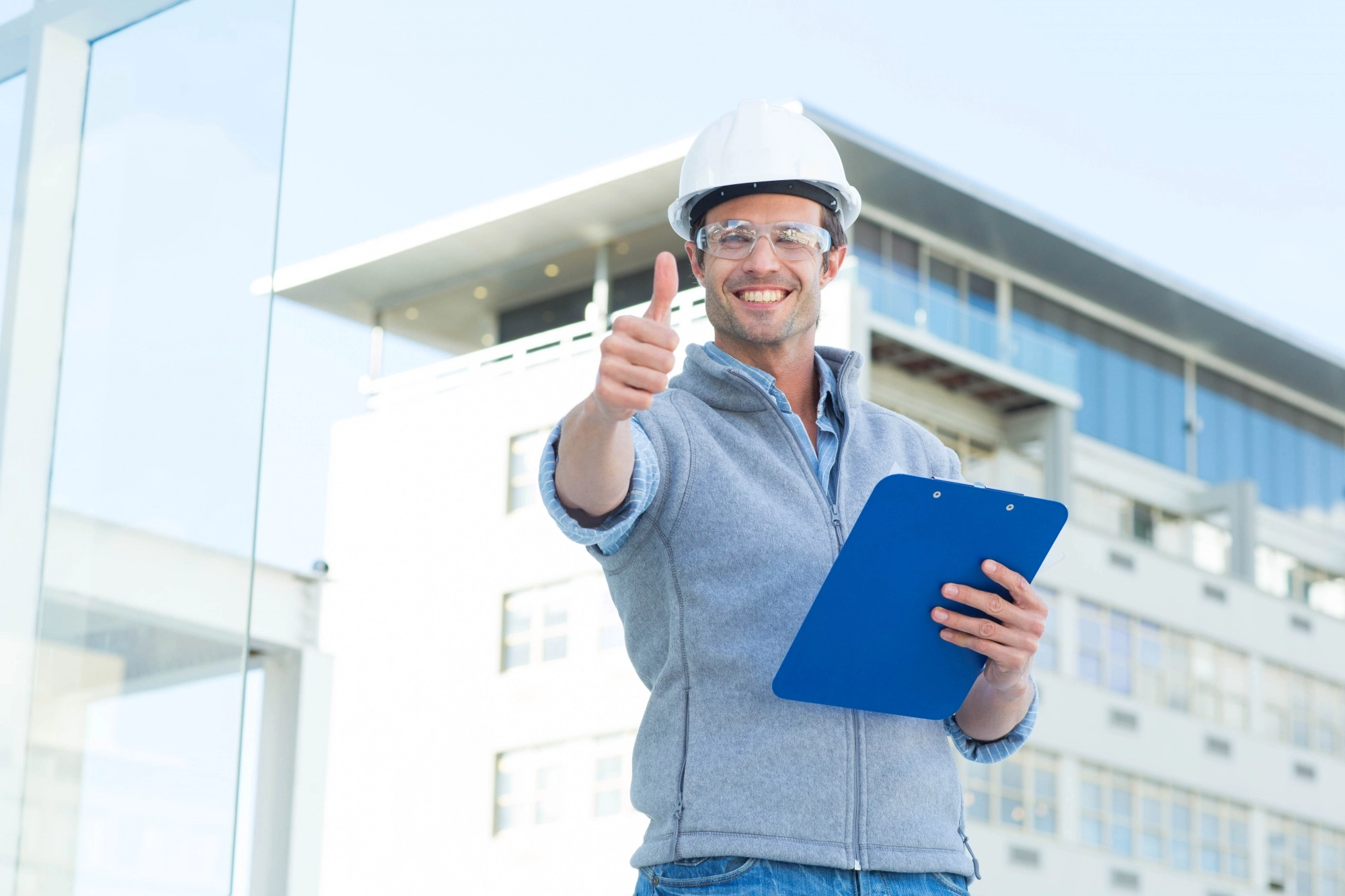 Engenheiro com capacete dando joinha na frente de uma obra